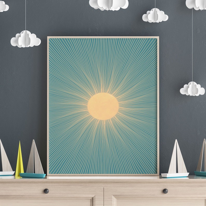 May include: A framed print of a stylized sun with radiating lines in shades of yellow and teal against a blue background.