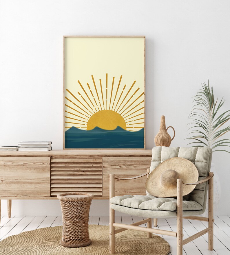 May include: A digital print of a minimalist sun rising over a blue ocean. The sun is yellow and the rays are gold. The ocean is a deep blue with waves. The background is a light yellow.