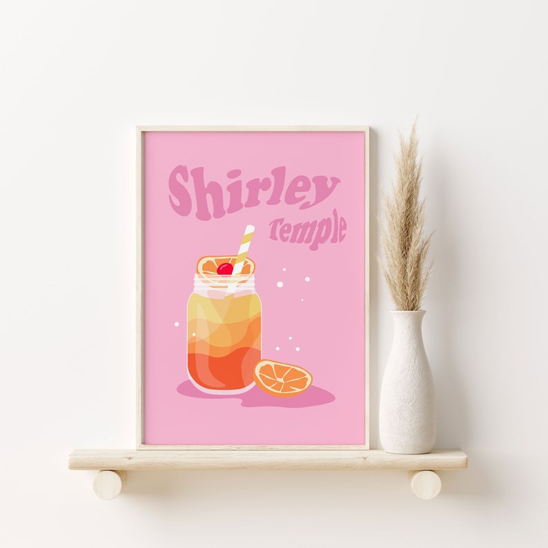 May include: A pink printable poster with the text "Shirley Temple" in a retro font. A mason jar filled with a layered orange and yellow drink with a cherry and straw is pictured. A slice of orange is on the table next to the jar.