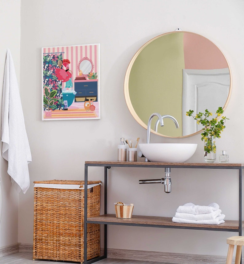 May include: A bathroom vanity with a white porcelain sink and a round mirror with a gold frame. The vanity has a wooden top and a black metal frame. There is a wicker laundry basket on the left side of the vanity.