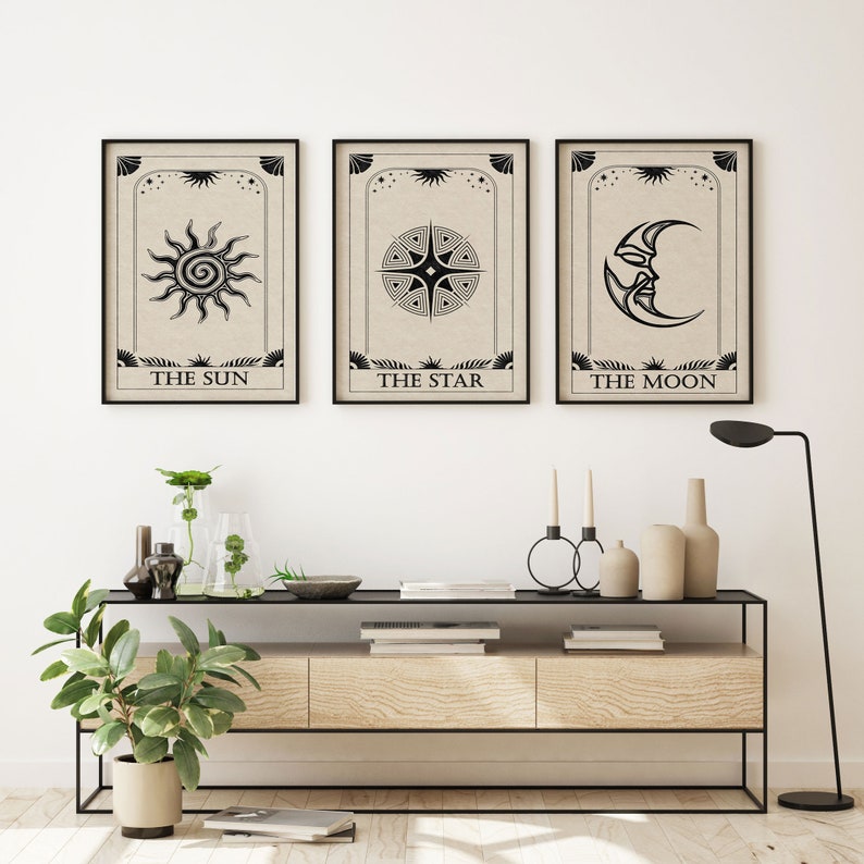 May include: Three black and white tarot card prints with a beige background. The prints feature illustrations of the sun, a star, and the moon. The text below each print reads "The Sun", "The Star", and "The Moon".