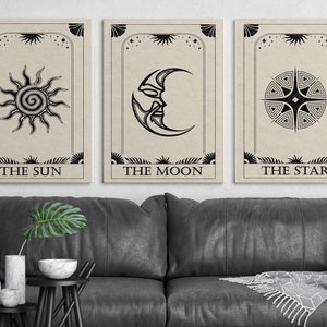 May include: Three black and white tarot cards with illustrations of the sun, moon, and star. The cards have a beige background and the text "The Sun", "The Moon", and "The Star" printed below the illustrations.