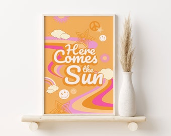 Puede incluir: Una impresión de estilo retro con un fondo melocotón y líneas onduladas rosas y naranjas. El texto "Here Comes the Sun" está en negrita, en blanco. La impresión presenta varios gráficos de estilo retro, incluyendo estrellas, signos de paz y caras sonrientes.