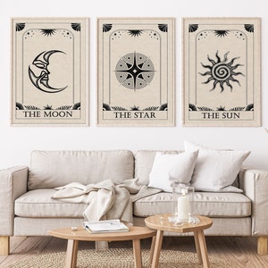 May include: Three black and white tarot card prints with a beige background. The cards are titled "The Moon", "The Star", and "The Sun". Each card features a stylized image of the moon, a star, and the sun.