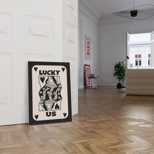 Pu&ograve; includere: Illustrazione in bianco e nero di una carta da gioco della regina di cuori con il testo "LUCKY US" su uno sfondo bianco.