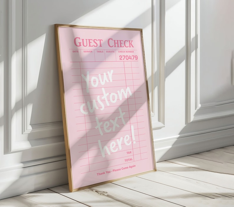 May include: A pink guest check with a gold frame. The check has a grid pattern and the text "GUEST CHECK" at the top. The text "Your custom text here!" is written in white cursive font. The check number is 270479.