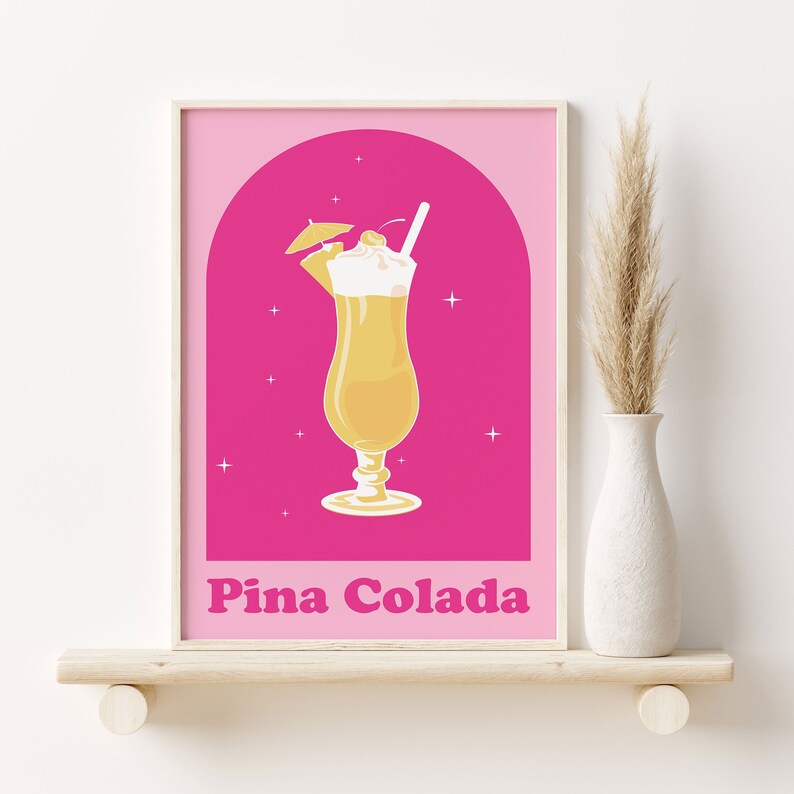 Puede incluir: Un p&oacute;ster rosa con marco blanco que presenta una ilustraci&oacute;n amarilla y blanca de un c&oacute;ctel Pina Colada con una cereza y una sombrilla peque&ntilde;a. El texto "Pina Colada" est&aacute; escrito en letras rosas negritas en la parte inferior del p&oacute;ster.