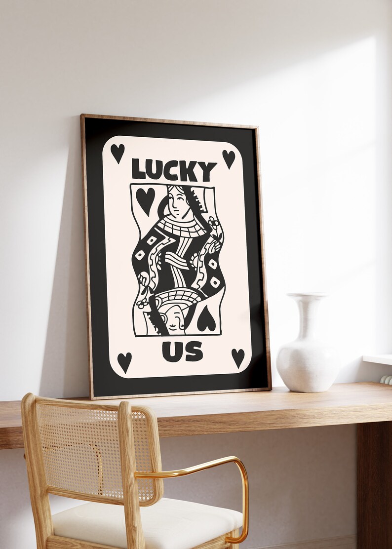 Pu&ograve; includere: Stampa in bianco e nero di una carta da gioco della Regina di Cuori con il testo "LUCKY US" su uno sfondo rosa.