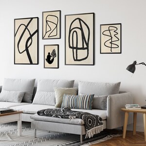 May include: A living room with a gray sectional sofa, black and white throw pillows, and a black and white throw blanket. There are five black framed abstract art prints on the wall above the sofa.
