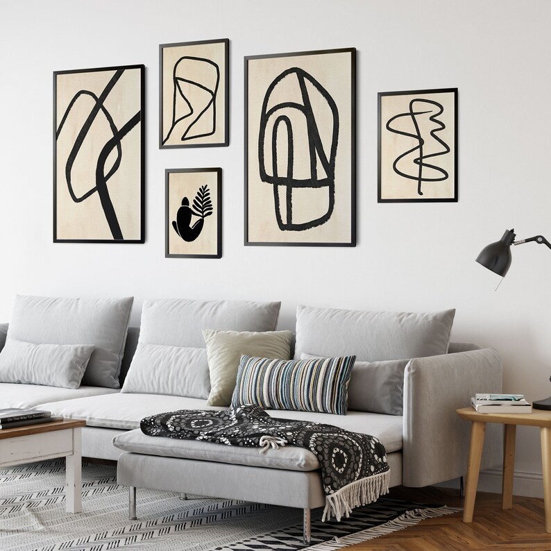 May include: A living room with a gray sectional sofa, black and white throw pillows, and a black and white throw blanket. There are five black framed abstract art prints on the wall above the sofa.