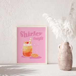 May include: A pink printable poster with the text "Shirley Temple" in a retro font. The poster features a cartoon illustration of a glass jar with a yellow and orange drink, a cherry, and a straw. A slice of orange is next to the jar.
