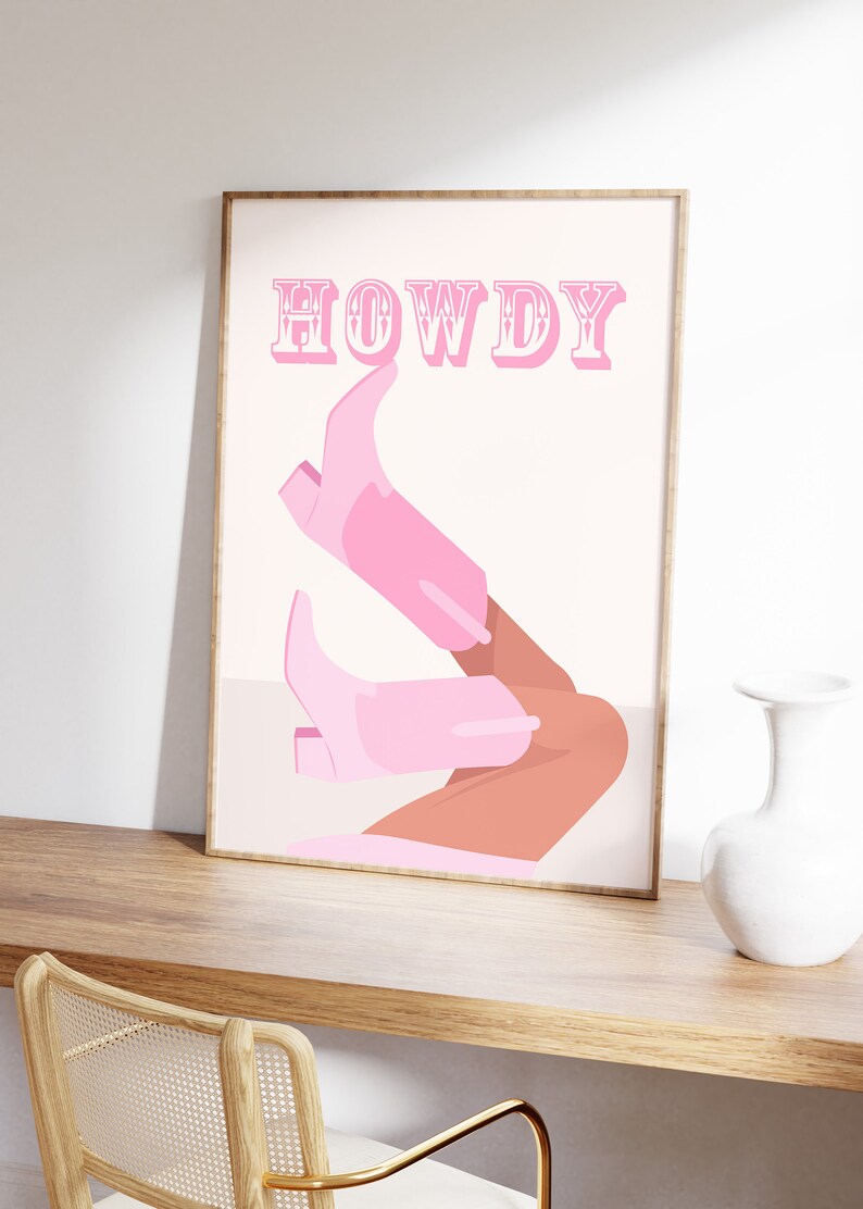 Pu&ograve; includere: Un poster rosa e bianco con la parola "HOWDY" in grandi lettere rosa. Il poster presenta un paio di stivali da cowboy rosa con una gamba abbronzata che sporge dalla parte superiore di ogni stivale.