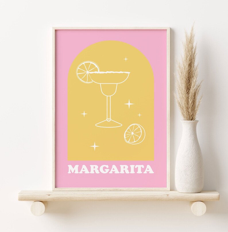 Puede incluir: Una impresi&oacute;n de arte de pared imprimible rosa y amarilla con un contorno blanco de un vaso de margarita y rodajas de lima. El texto "MARGARITA" est&aacute; en la parte inferior de la impresi&oacute;n.