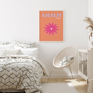 K&ouml;nnte beinhalten: Ein wei&szlig; gerahmtes Poster mit orangefarbenem Hintergrund und einer stilisierten rosa Blume. Der Text auf dem Poster lautet "Amalfi Italien".