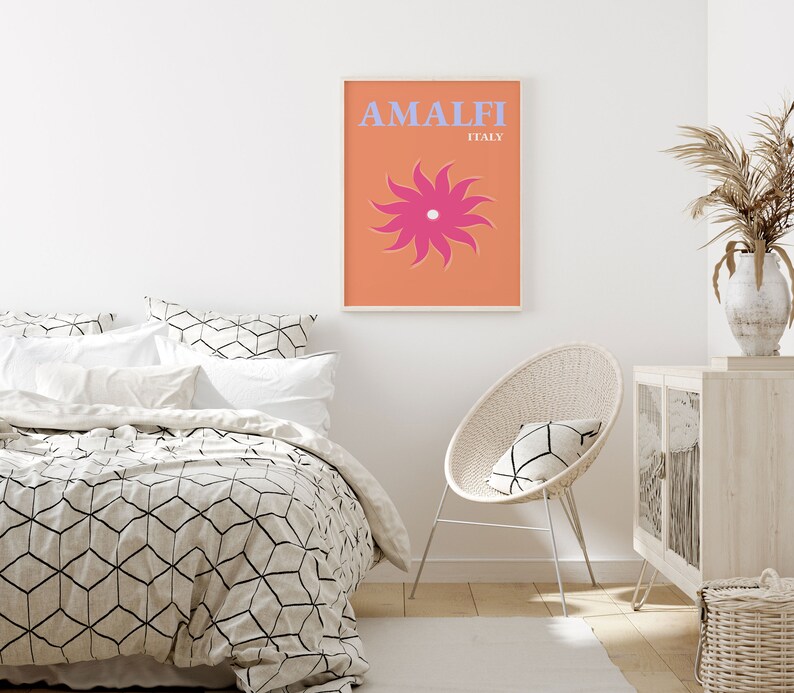 K&ouml;nnte beinhalten: Ein wei&szlig; gerahmtes Poster mit orangefarbenem Hintergrund und einer stilisierten rosa Blume. Der Text auf dem Poster lautet "Amalfi Italien".