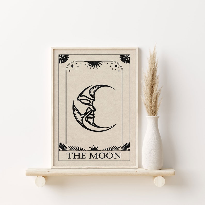 May include: A black and white illustration of the moon with a face on it. The moon is surrounded by stars and a sun. The text "THE MOON" is printed below the moon.