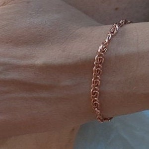 May include: A rose gold chain bracelet with a delicate, intricate design. The bracelet is made of metal and has a polished finish.