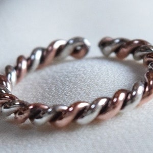 Peut inclure: Une bague torsadée en argent et or rose. La bague est composée de deux métaux torsadés ensemble pour créer un design unique.