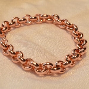 Puede incluir: Un brazalete de cadena de oro rosa con un diseño delicado y enlazado.
