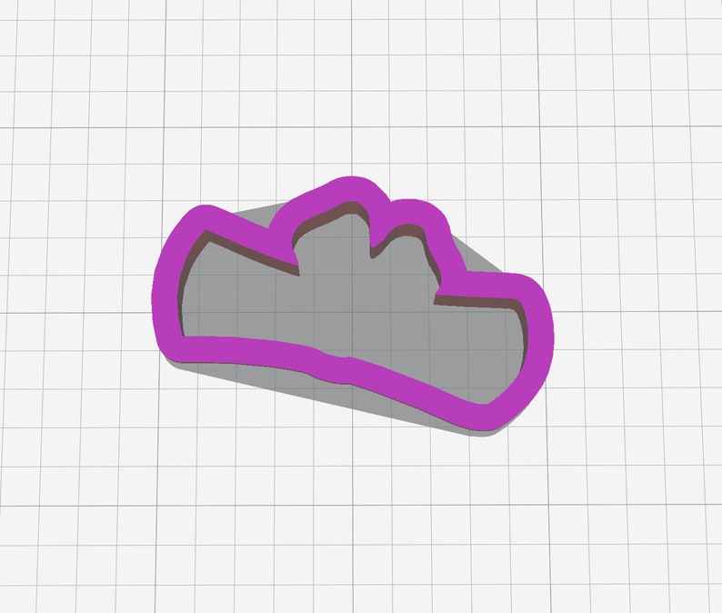 May include: A purple cloud-shaped cookie cutter. The cutter has a thick, rounded outline and a three-lobed top. The shadow beneath the cutter suggests a three-dimensional form. The background is a white grid.