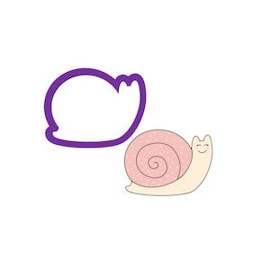 K&ouml;nnte beinhalten: Ein rosafarbener und wei&szlig;er Schnecken-Ausstecher mit einem l&auml;chelnden Gesicht. Der Ausstecher ist in Form einer Schnecke mit einer spiralf&ouml;rmigen Schale und einem kleinen K&ouml;rper.