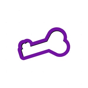 May include: A purple bone-shaped cookie cutter with a black outline. The cutter is designed with a handle and a bone shape, perfect for making dog treats or themed cookies. The cutter is set against a white background.