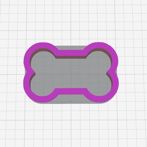 May include: A purple plastic dog bone cookie cutter. The cookie cutter is on a white grid background.