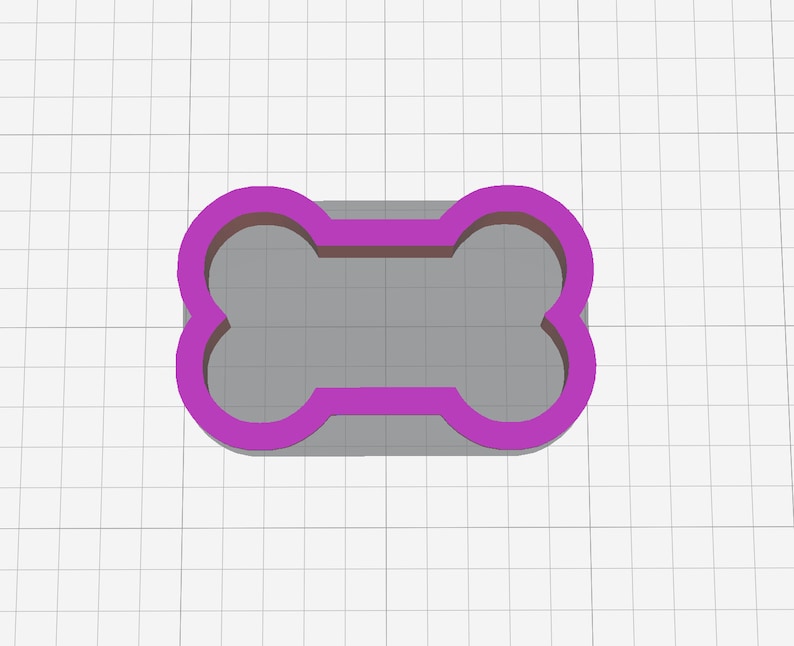 May include: A purple plastic dog bone cookie cutter. The cookie cutter is on a white grid background.
