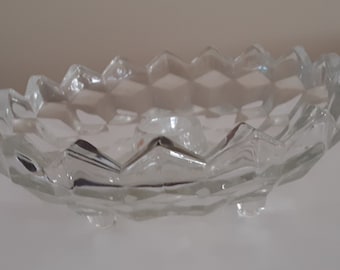 May include: A clear glass bowl with a diamond pattern and three legs.
