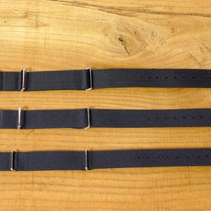May include: Three black nylon watch straps with silver hardware. The straps are 18mm, 20mm, and 22mm wide.