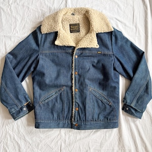 May include: A rustic wooden sign with the text "Welcome to our home" in white lettering. The sign features a distressed finish and a simple, inviting design, perfect for front door decor.