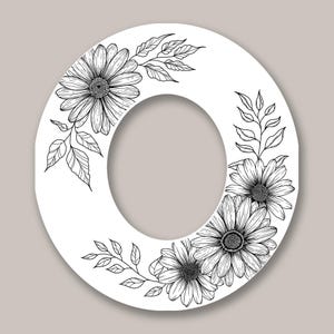 Pode incluir: Uma letra "O" branca decorada com desenhos detalhados a tra&ccedil;o preto de margaridas e folhas. O design floral &eacute; disposto ao redor da borda externa da letra, criando uma apar&ecirc;ncia decorativa e elegante. O fundo &eacute; de uma cor neutra s&oacute;lida.