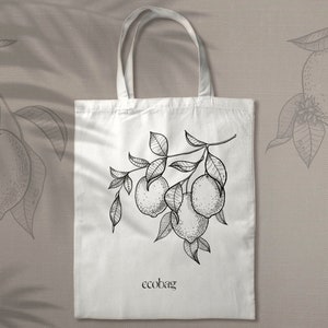 Pu&ograve; includere: Borsa tote bianca con un disegno a linea nera di un ramo di limone con foglie e frutti. Il testo "ecobag" &egrave; stampato in nero nella parte inferiore della borsa.