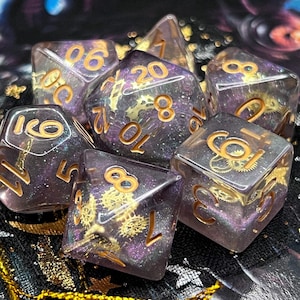 以下が含まれることがあります： キラキラ光るパープルとゴールドのサイコロ6個セット。サイコロは1から20まで番号が振られており、スチームパンクのデザインが施されています。