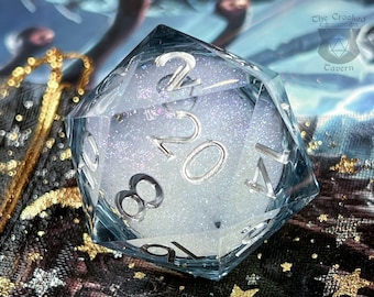 May include: A twenty-sided die made of clear resin with a white, glittery, cloud-like core. The die features silver-colored numbers engraved on its faces. The top face displays the number 20. The logo for The Crooked Tavern is visible in the corner.