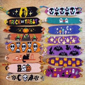 May include: A collection of handmade Halloween-themed friendship bracelets. Designs include cats, skulls, pumpkins, bats, ghosts, and the phrase "Trick or Treat." Each bracelet is a unique, colorful accessory, perfect for the spooky season.