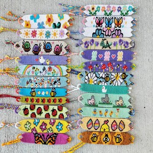 Może przedstawiać: Kolekcja 18 kolorowych bransoletek przyjaźni z różnymi wzorami, w tym motylami, ślimakami, kwiatami i pszczołami. Bransoletki są wykonane z kolorowej nici do haftu i są ze sobą związane węzłem na końcu.