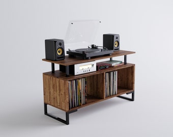 May include: A wooden record player stand with two shelves for storing vinyl records. The stand has a black metal frame and a turntable with a clear dust cover. There are two black speakers on the top shelf and a white amplifier on the lower shelf.