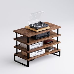 Könnte beinhalten: Ein vierstufiger Holz-Audio-Rack mit schwarzen Metallstützen. Die oberste Ablage hat einen Plattenspieler mit einer durchsichtigen Staubschutzhaube. Die anderen Ablagen haben Audiogeräte, darunter ein Receiver, ein Verstärker und ein Kassettenspieler.