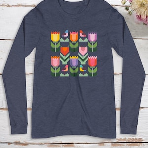 Pode incluir: Uma camiseta de manga comprida azul marinho com um design geométrico de tulipas e pássaros coloridos.