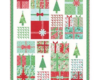 May include: A Christmas-themed quilt featuring a repeating pattern of wrapped gifts and Christmas trees. The gifts are in red, green, and blue, with various patterns and bows. The quilt has a white background and a red and green striped border.