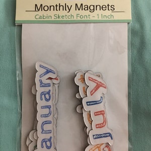 May include: A set of 12 magnetic monthly calendar labels in a cabin sketch font. The labels are 1 inch in size and are packaged in a clear plastic bag with a white header card that reads "Monthly Magnets - Cabin Sketch Font - 1 Inch".