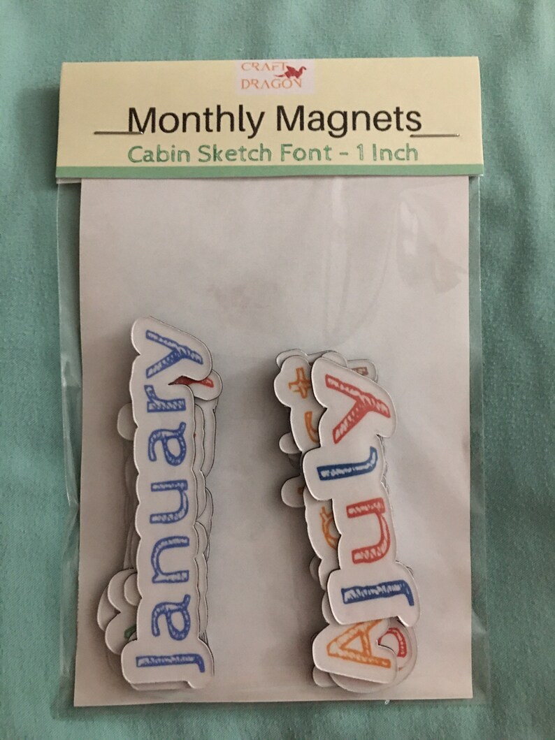 May include: A set of 12 magnetic monthly calendar labels in a cabin sketch font. The labels are 1 inch in size and are packaged in a clear plastic bag with a white header card that reads "Monthly Magnets - Cabin Sketch Font - 1 Inch".