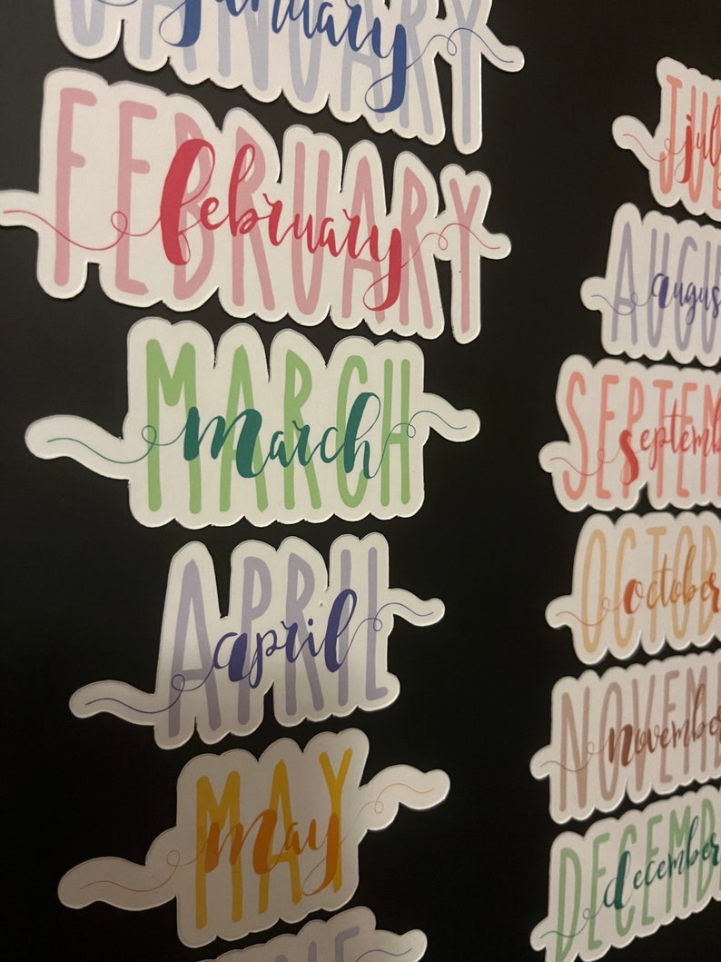 Puede incluir: Pegatinas coloridas con los meses del a&ntilde;o en escritura a mano. Cada mes es de un color diferente, incluyendo rojo, verde, azul y amarillo. Las pegatinas tienen un borde blanco y est&aacute;n dispuestas sobre un fondo negro.