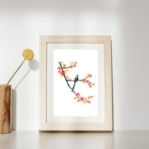 Könnte beinhalten: Ein gerahmter Druck eines Aquarells, das einen schwarzen Vogel auf einem Zweig mit roten und gelben Blüten zeigt. Der Hintergrund ist weiß.