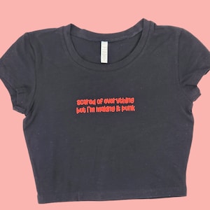 Może przedstawiać: Czarny crop top z haftem w kolorze czerwonym, na którym widnieje napis "scared of everything but I'm making it punk."