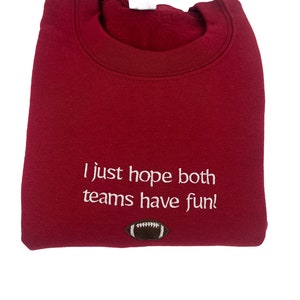 May include: Burgundy sweatshirt with white text that reads "I just hope both teams have fun!" and a brown football graphic.
