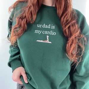 May include: A dark green sweatshirt with the text "ur dad is my cardio" and a small embroidered image of a person doing yoga.