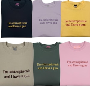 May include: Six crew neck sweatshirts in various colors: navy, lavender, yellow, tan, dark green, and pink. Each sweatshirt has the embroidered text "I'm schizophrenic and I have a gun" in a contrasting color.