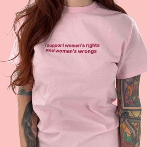 Puede incluir: Camiseta rosa con el texto "I support women's rights and women's wrongs" impreso en rojo.